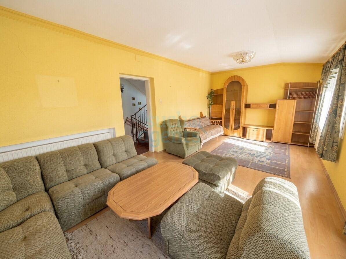 Geräumiges Wohnzimmer mit gelben Wänden, bequemen Sofas und traditionellen Holzmöbeln.