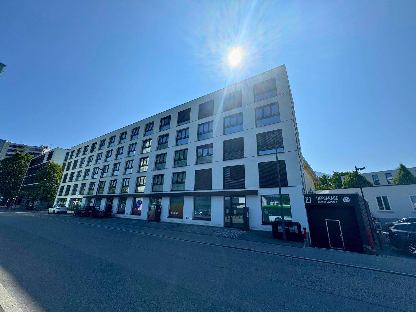 Modernes Geschäftsgebäude mit mehreren Etagen und großen Fenstern unter strahlend blauem Himmel.
