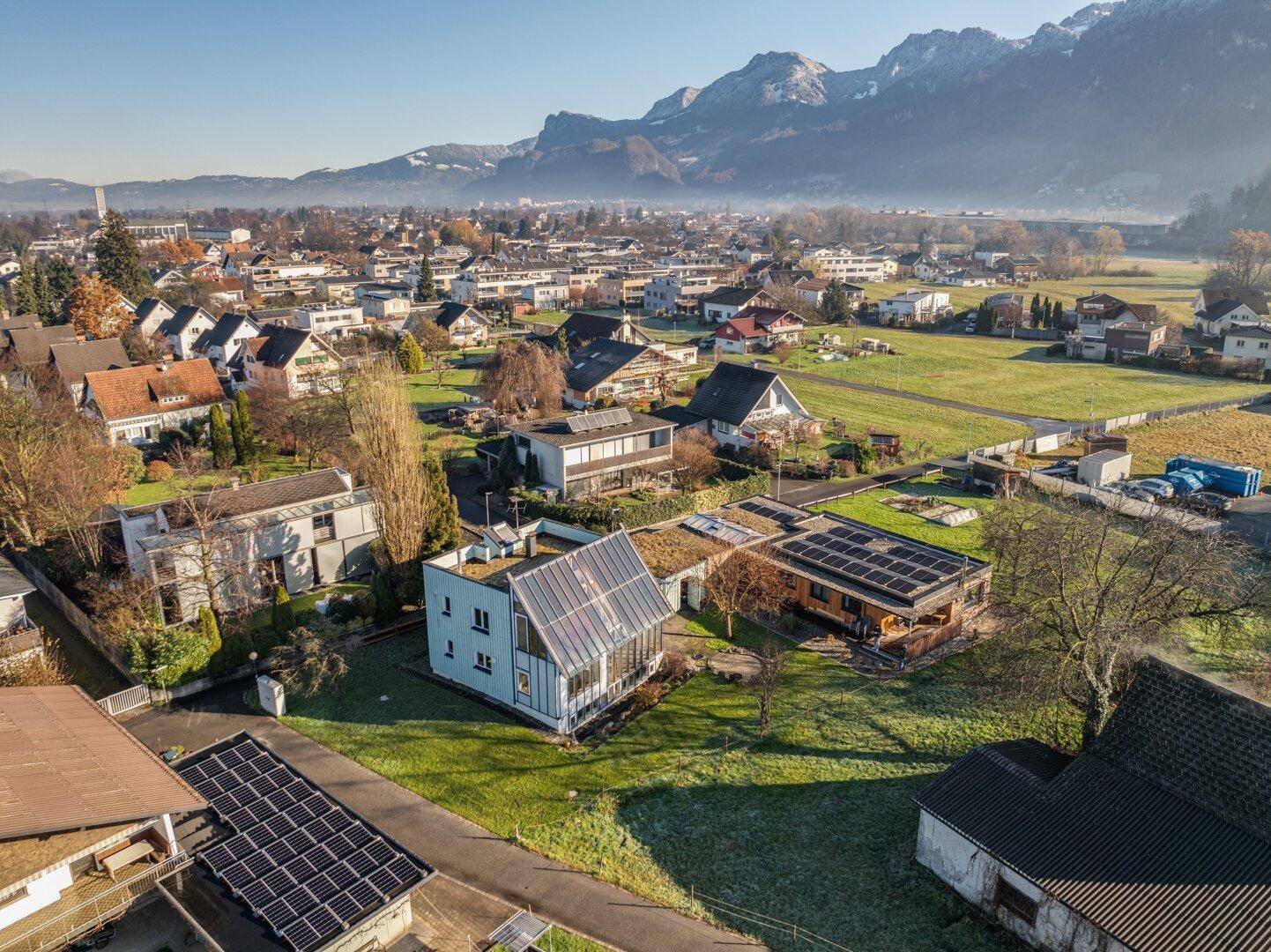 Weitläufige Wohnsiedlung mit Bergblick und vielen Häusern mit Solaranlagen unter strahlendem Himmel.
