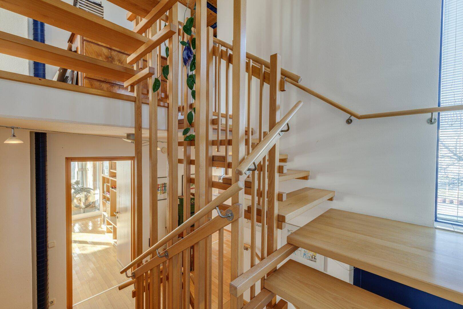 Offenes Treppenhaus aus Holz mit natürlichem Lichteinfall und Blick in den unteren Bereich.