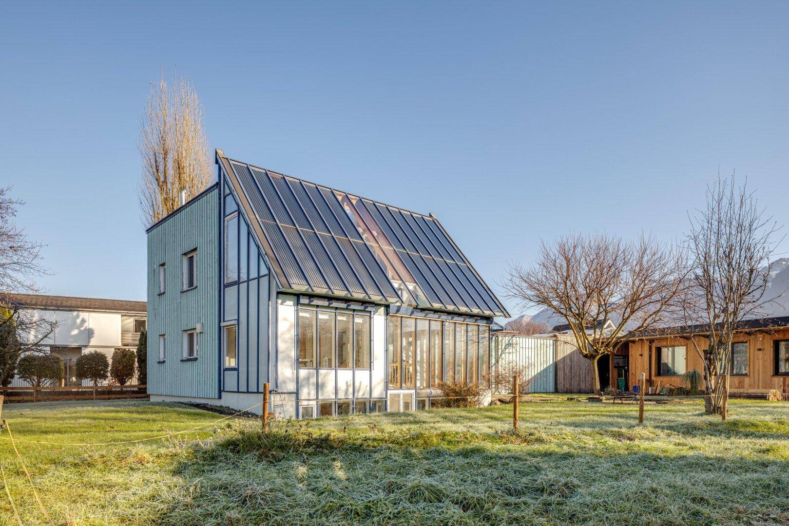 Modernes Haus mit Solardach, großen Glasflächen und weitem Blick in die Landschaft.