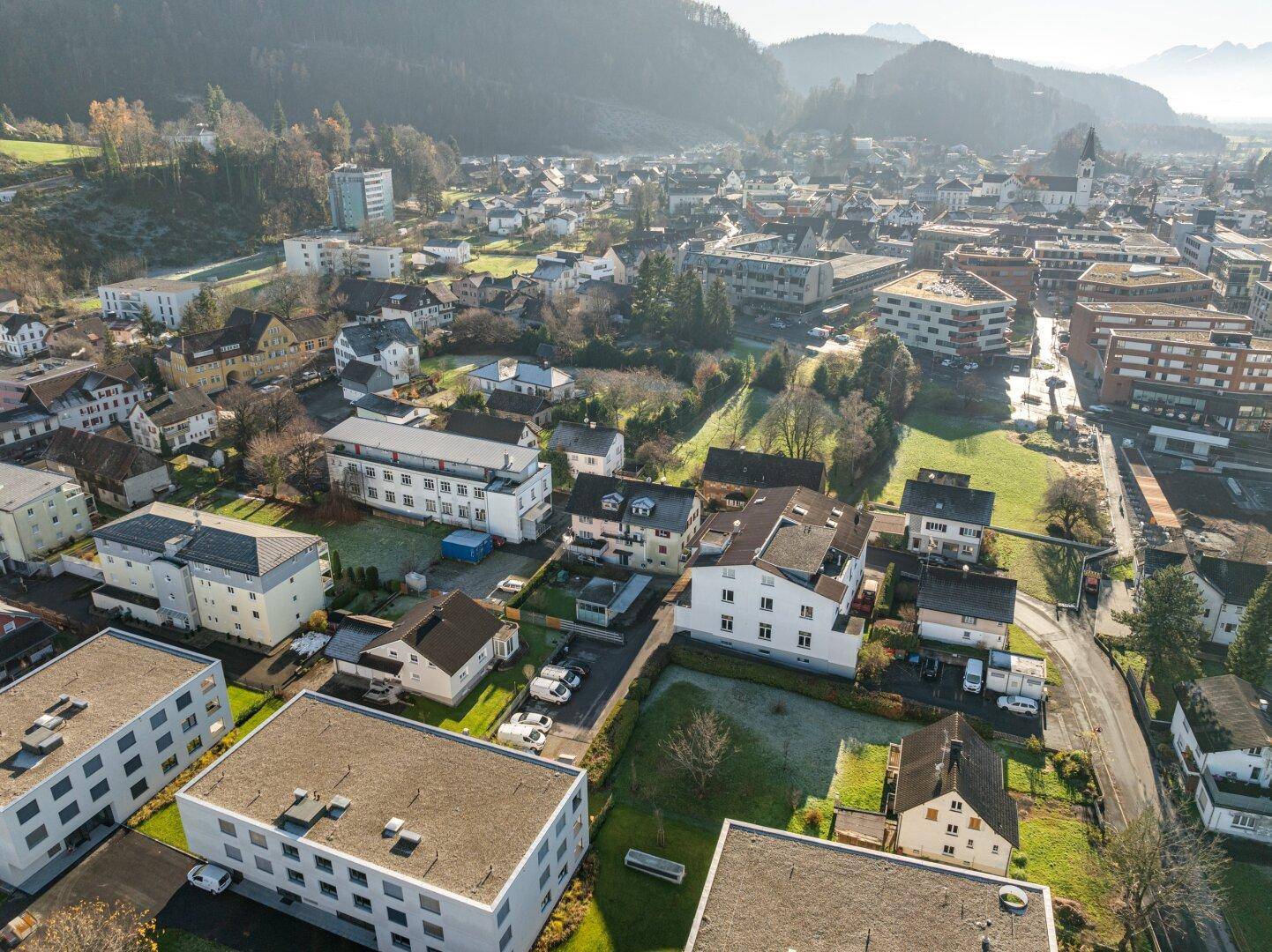 Luftaufnahme einer Wohnsiedlung mit Häusern und Bergen im Hintergrund.