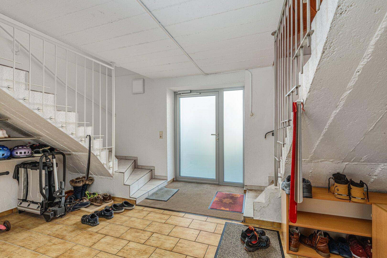 Eingangsbereich im Untergeschoss mit Treppenaufgang und Fliesenboden.