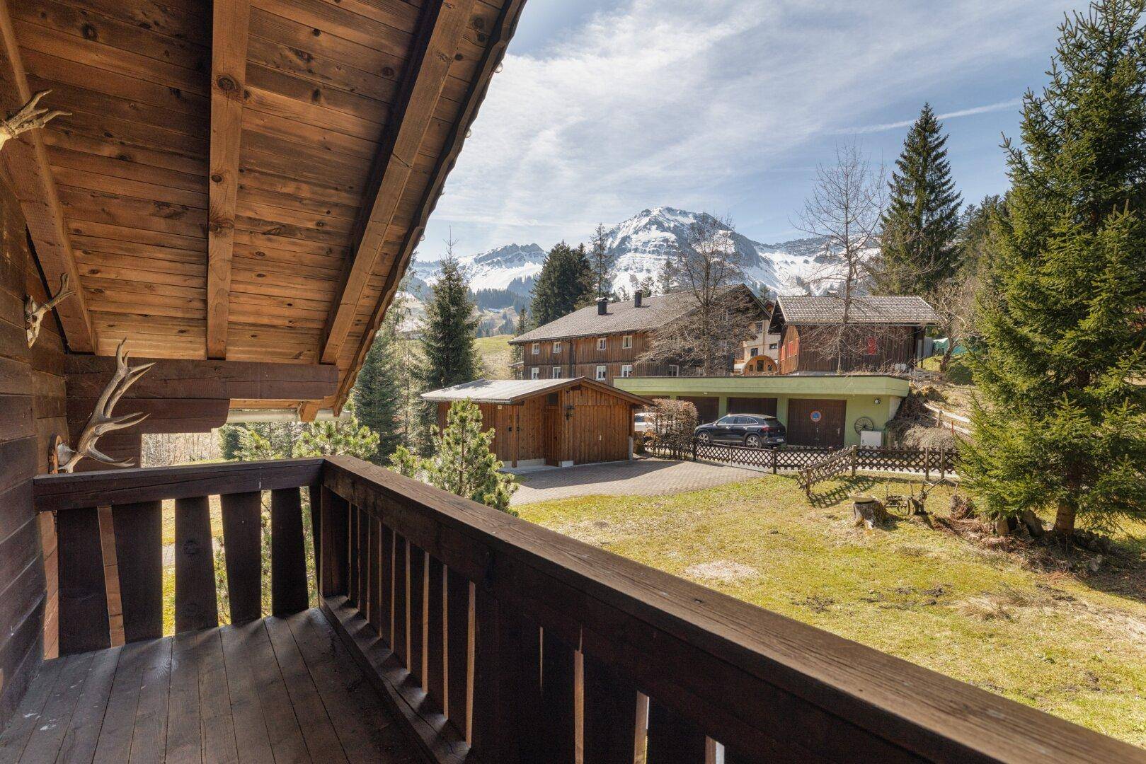 Balkon mit Holzboden und Geländer, bietet einen weiten Blick auf die umliegende Berglandschaft.
