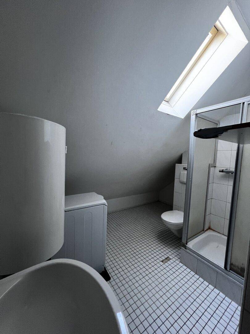 Dachgeschoss-Badezimmer mit Dusche, WC, Waschmaschine und Dachfenster.