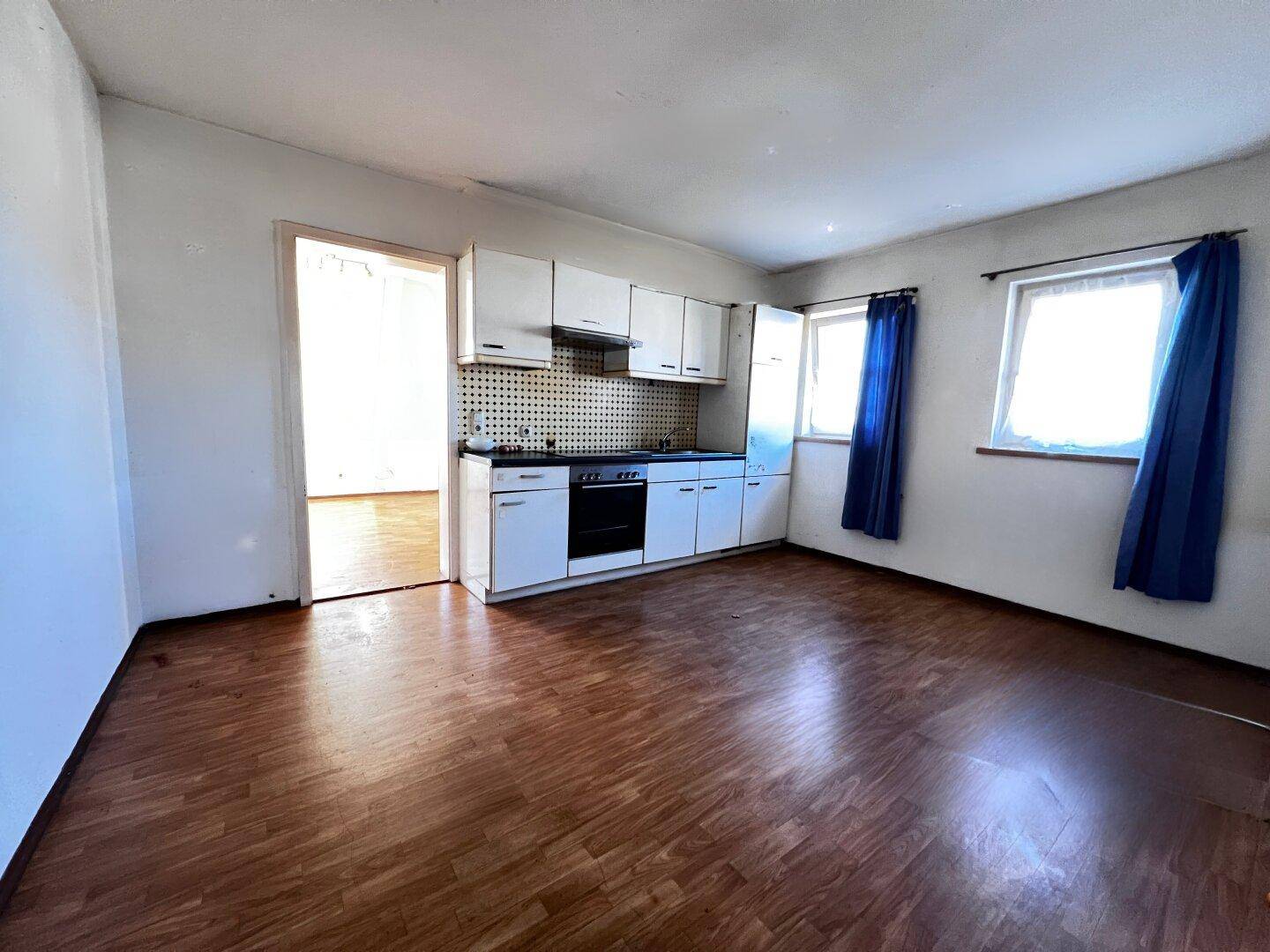 Einfache Küchenzeile mit Herd und Spüle in einem Raum mit Laminatboden.