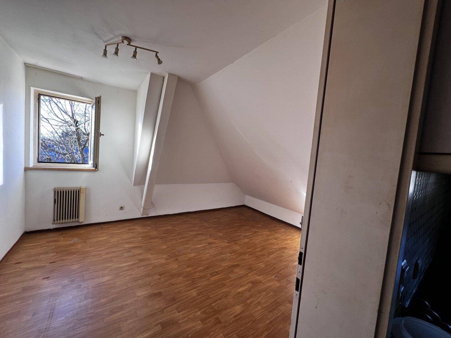 Helles Schlafzimmer im Dachgeschoss mit Laminatboden und schrägen Wänden.