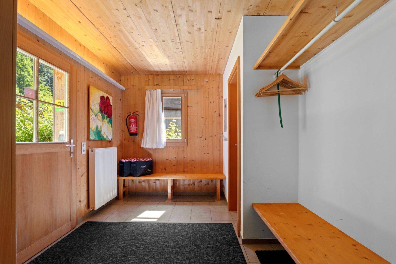 Eingangsbereich mit Holzboden, Sitzbank und Garderobe, hell und einladend gestaltet.