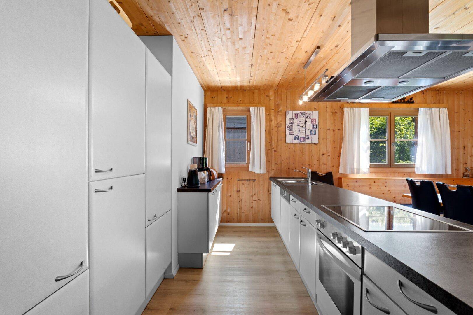 Moderne Küche mit weißen Schränken, Induktionskochfeld und Holzwänden im Landhausstil.