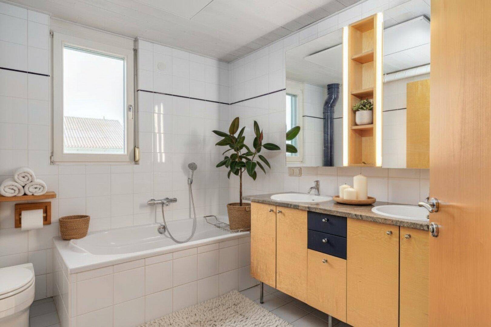 Modernes Badezimmer mit Badewanne, Doppelwaschbecken und großem Spiegel.