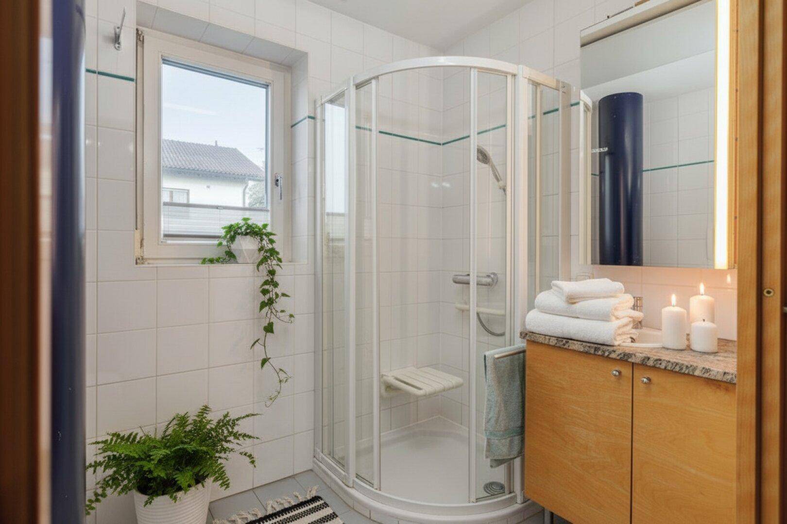 Helles Badezimmer mit Duschkabine, Fenster und modernen Armaturen.