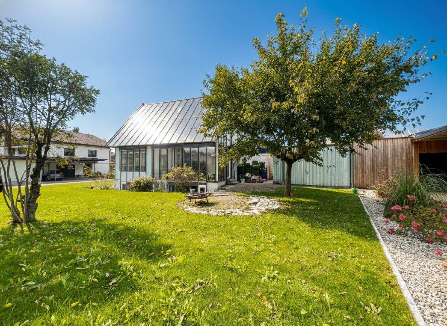 Großer Garten mit Rasenfläche, Obstbaum und einem Haus mit Solardach.