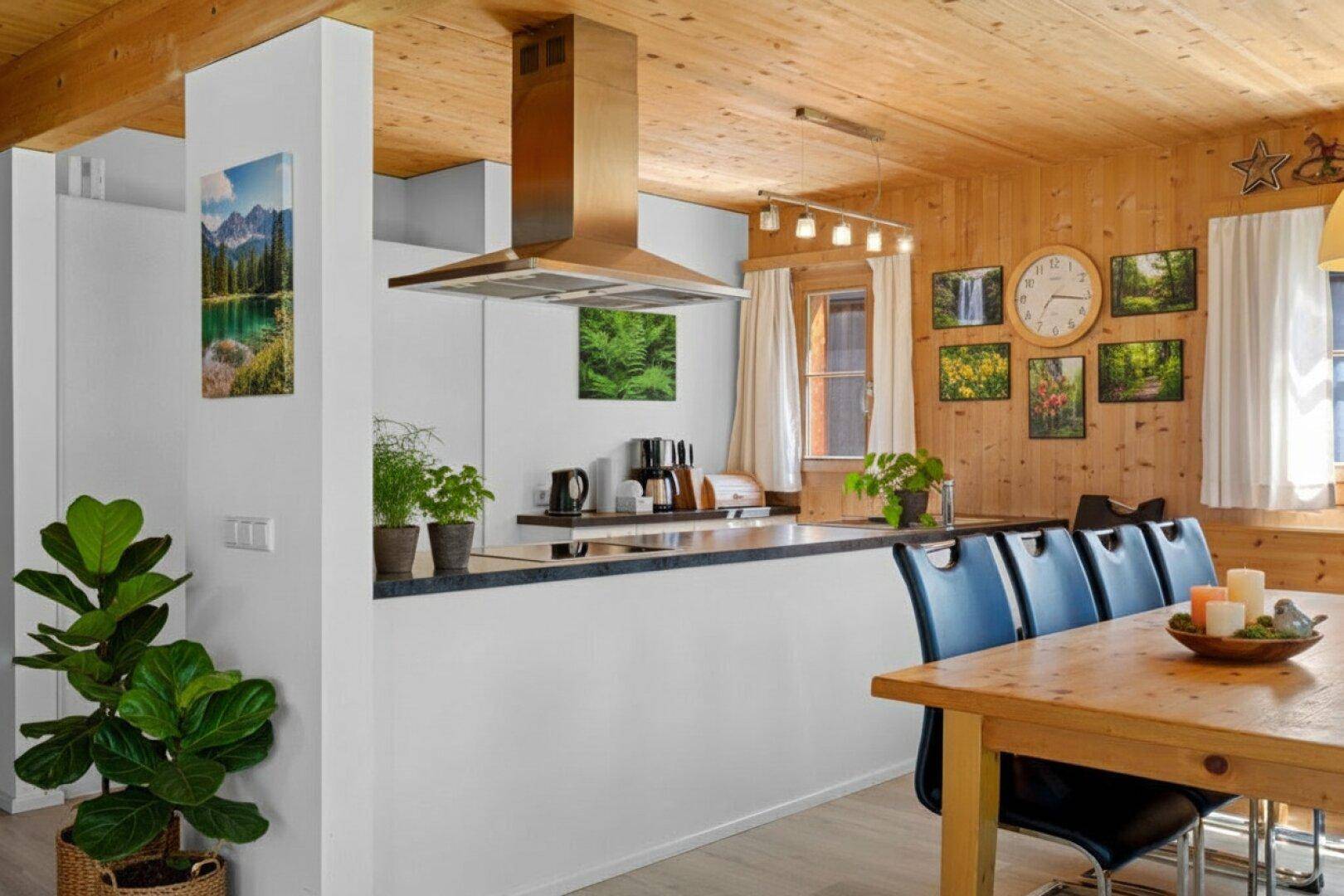 Offene Küche mit Holzbalkendecke, moderner Dunstabzugshaube und Essbereich.