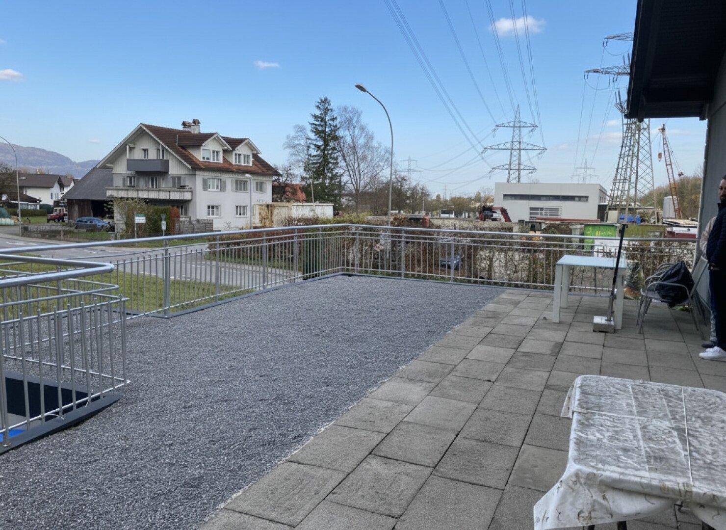 Große, gepflasterte Terrasse mit Kiesbereich und Metallgeländer, Blick auf die Umgebung.