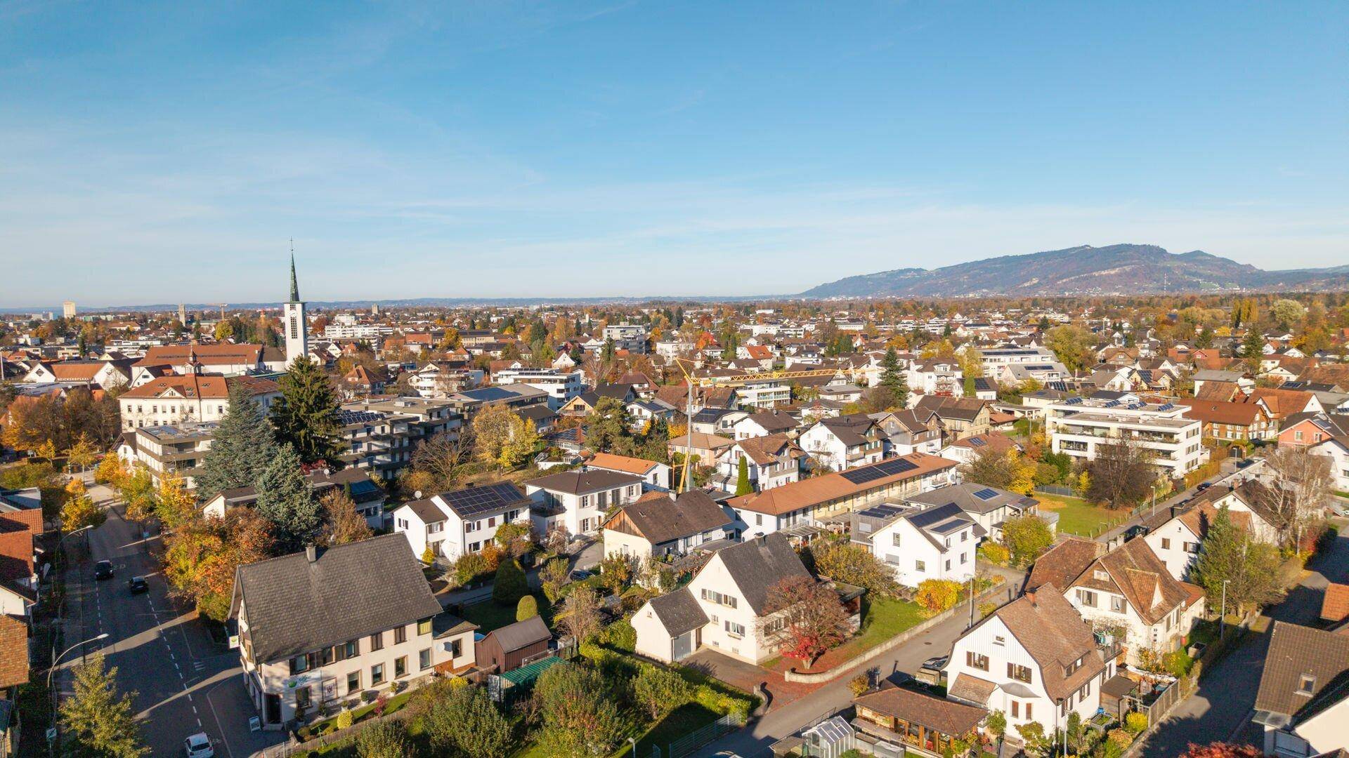 Weitläufige Luftaufnahme einer Stadt mit vielen Häusern und Bergen im Hintergrund.