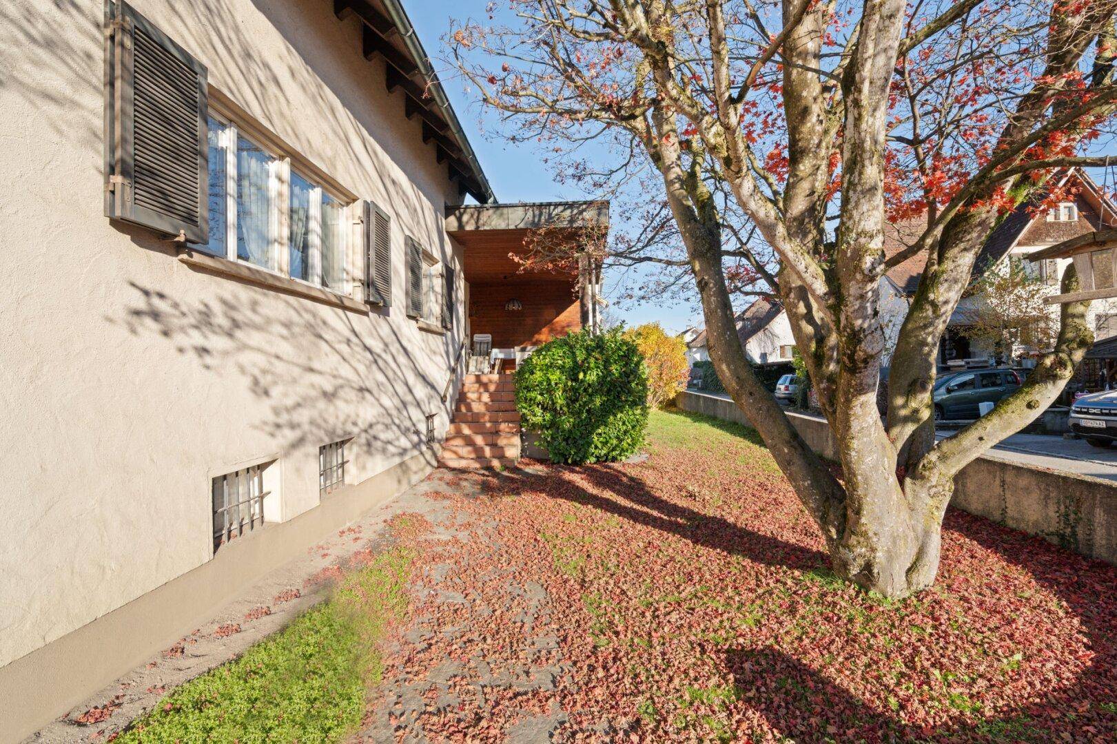 Seitliche Ansicht des Hauses mit überdachtem Terrassenbereich und Treppe im Freien.