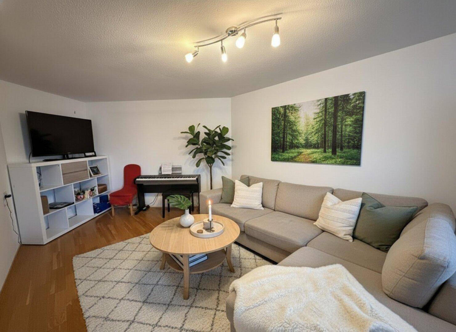 Modern eingerichtetes Wohnzimmer mit Sofa, Klavier und Fernseher.