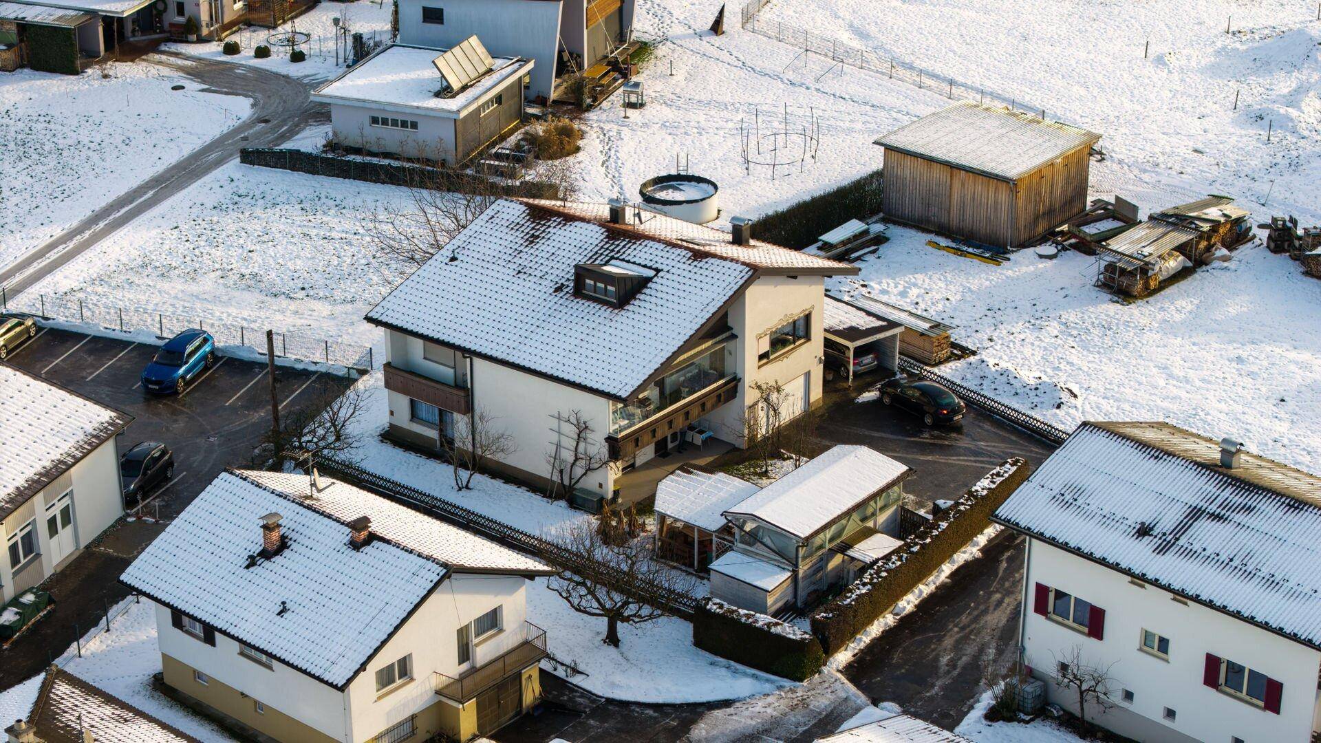Luftaufnahme des Wohnhauses und der Nachbarschaft im Winter mit schneebedeckten Dächern.