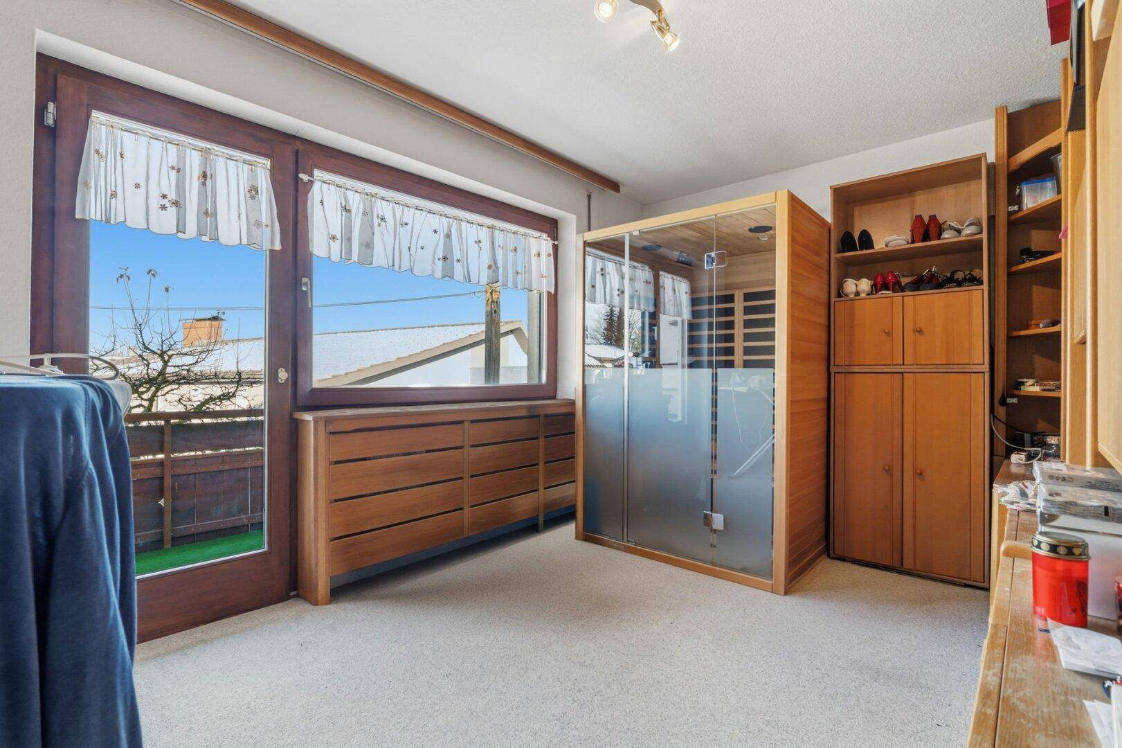 Raum mit Infrarotkabine, Teppichboden und Zugang zu einem kleinen Balkon.