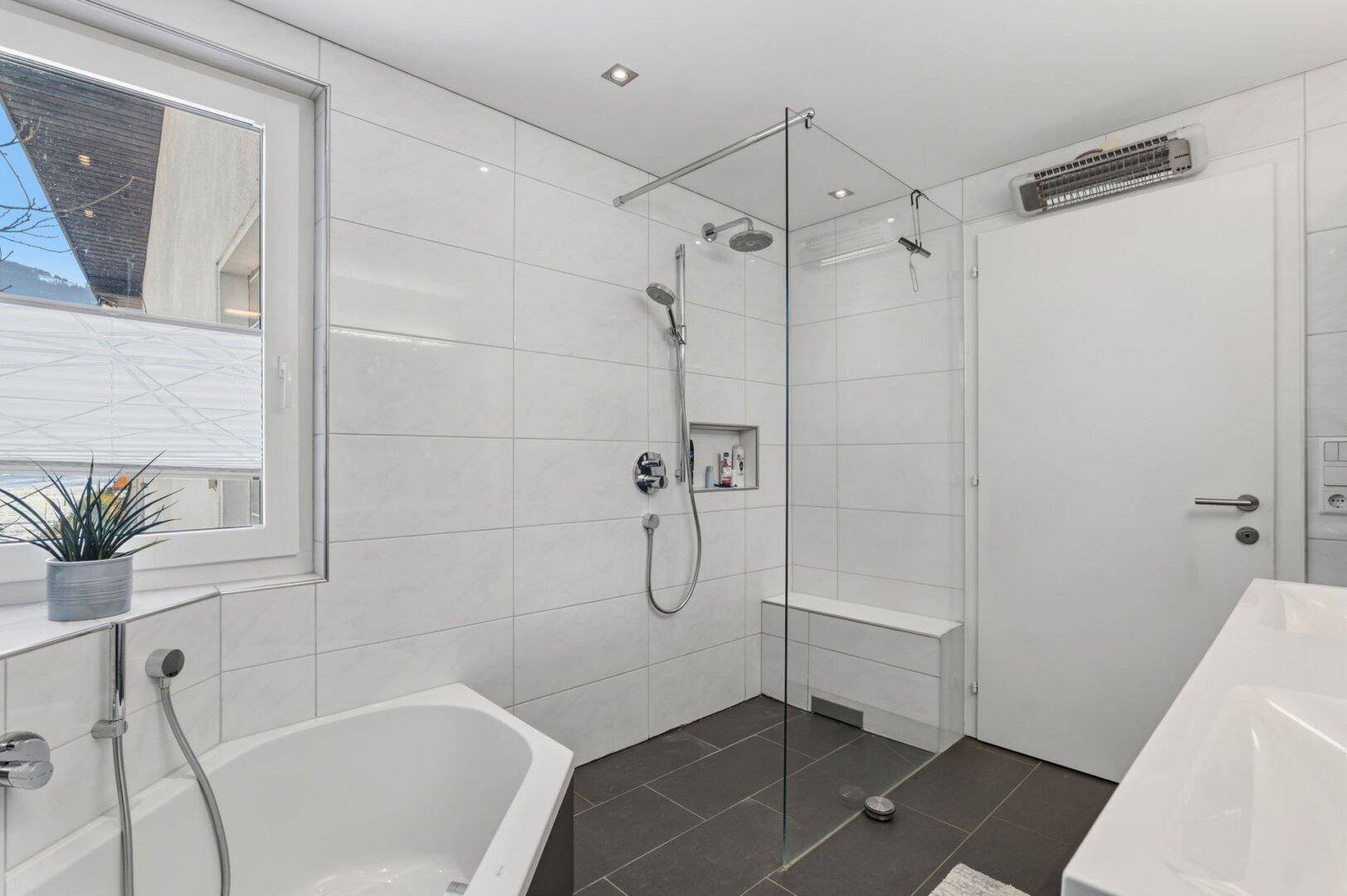 Modernes Badezimmer mit Badewanne, begehbarer Dusche und großformatigen Fliesen.