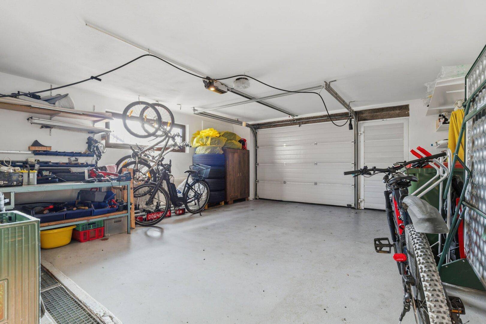 Geräumige Garage mit Stauraum, Werkbank und Platz für Fahrräder.