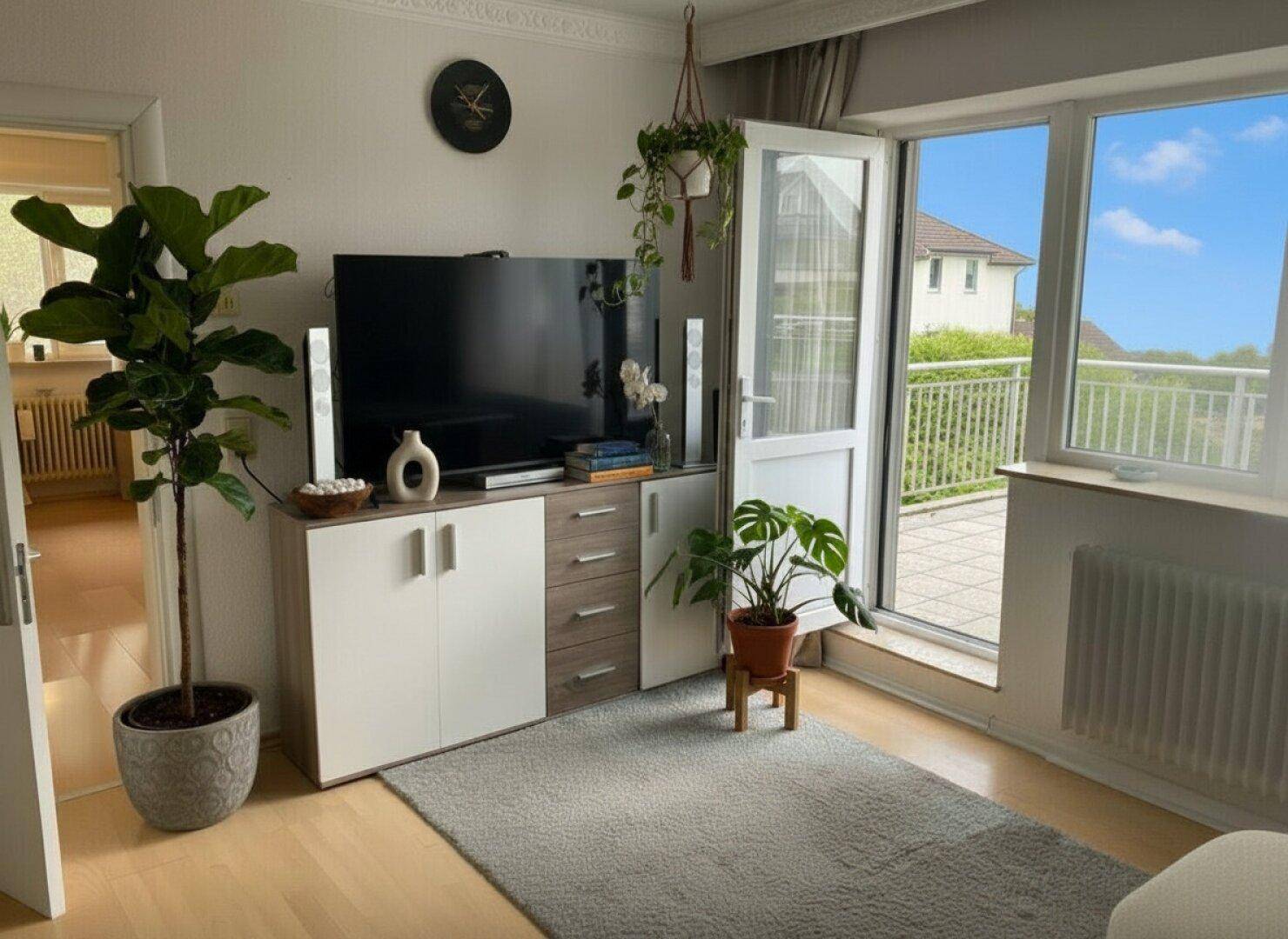 Helles Wohnzimmer mit Zugang zu einem Balkon, hellem Boden und modernen Möbeln.