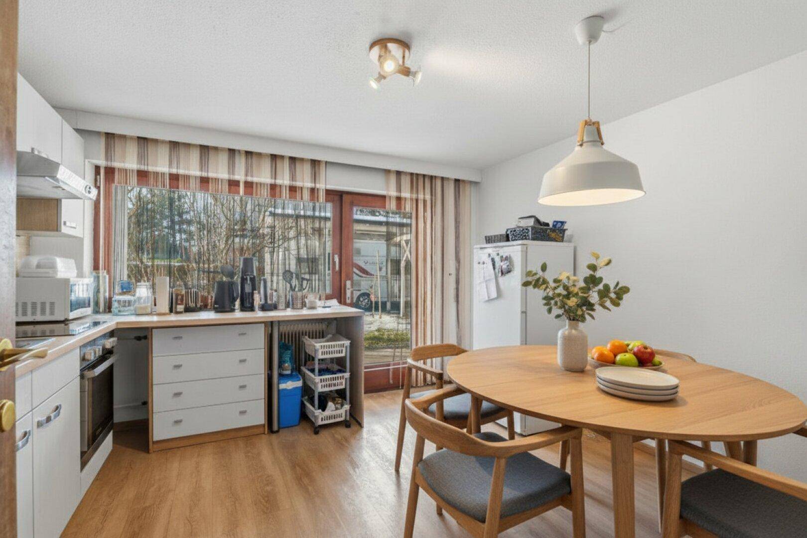 Helle Küche mit Essbereich, Holzboden und Zugang zum Außenbereich.