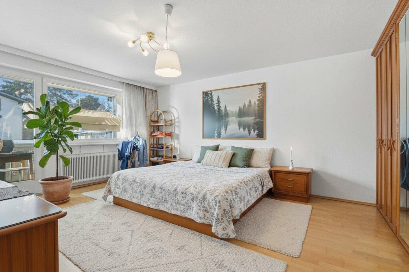 Helles Schlafzimmer mit Holzboden, großem Fenster und Kleiderschrank.