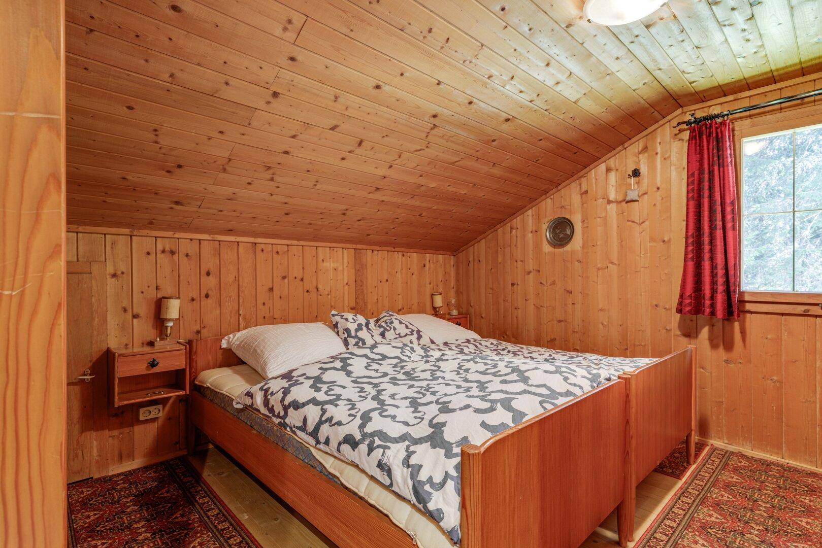 Rustikales Schlafzimmer mit Holztäfelung, schräger Decke und zwei Einzelbetten.