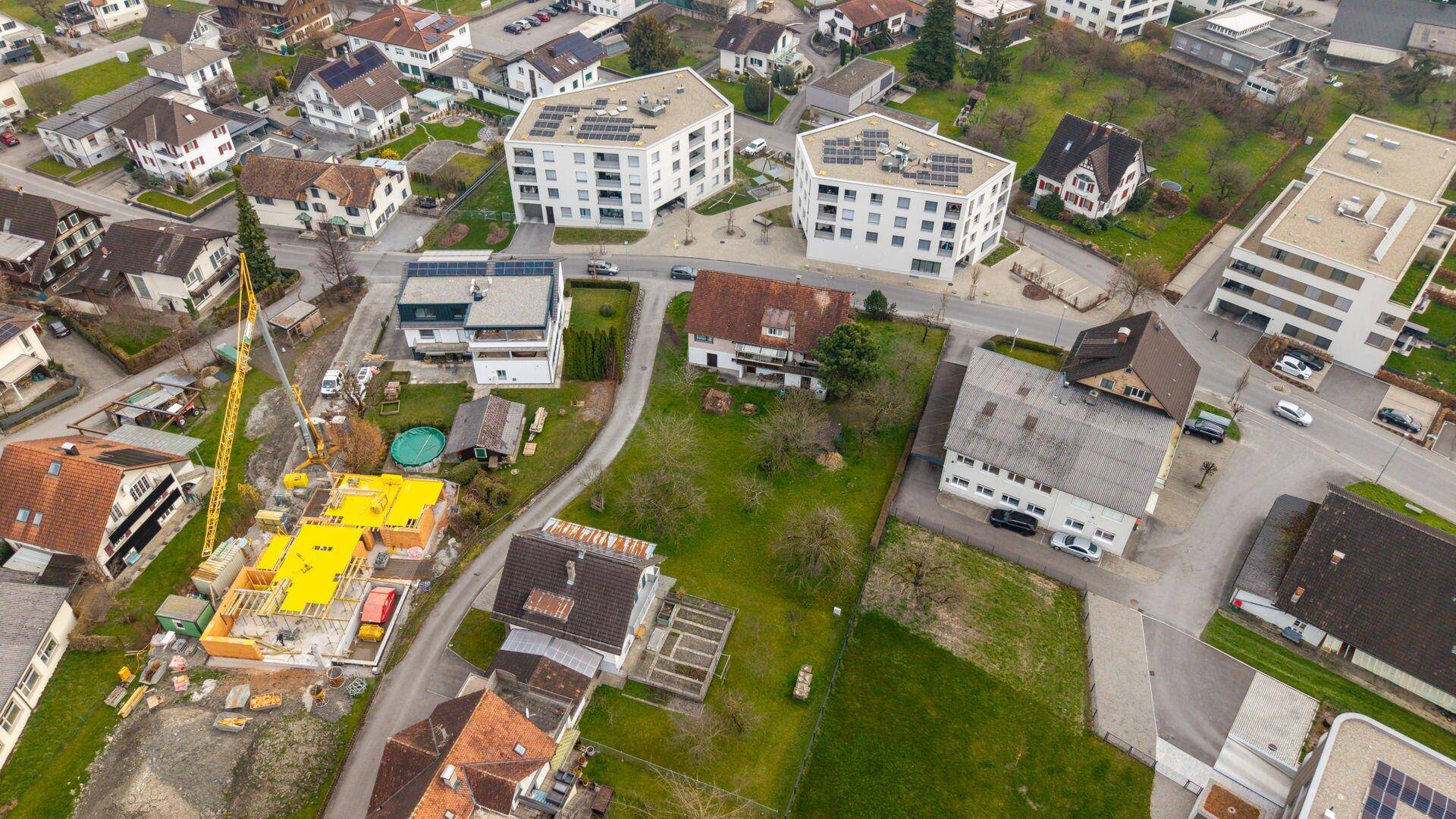 Detaillierte Luftaufnahme eines Wohnviertels mit bestehenden Häusern und einer Baustelle im Vordergrund.