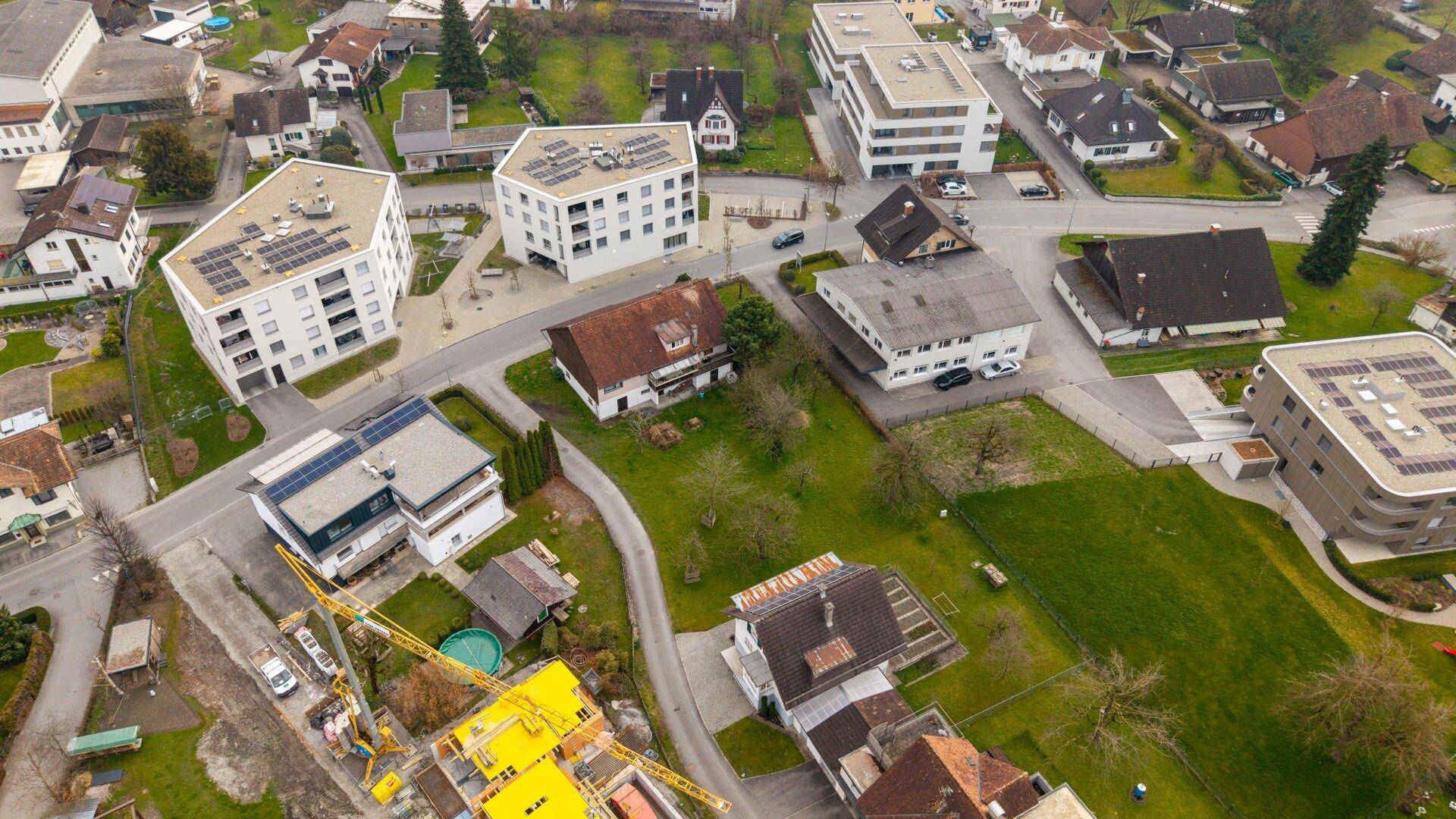 Überblick aus der Luft über ein Wohngebiet mit modernen und traditionellen Häusern sowie einer aktiven Baustelle.