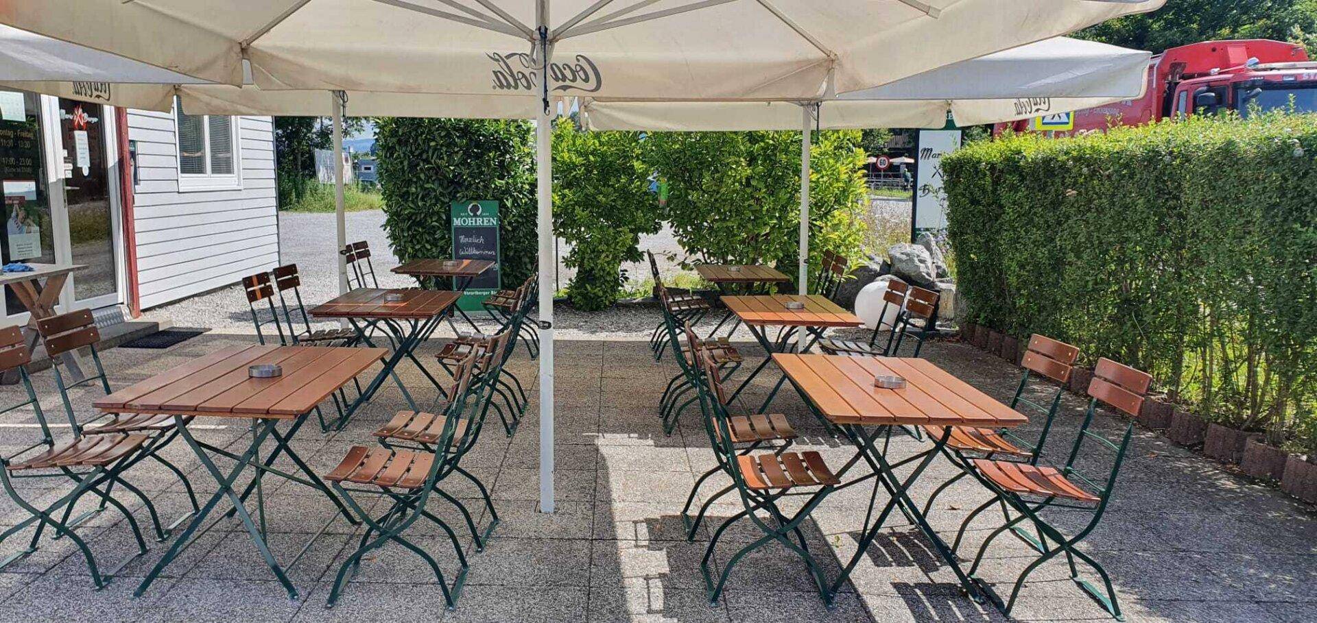 Große Außenterrasse eines Restaurants mit vielen Tischen, Stühlen und Sonnenschirmen.