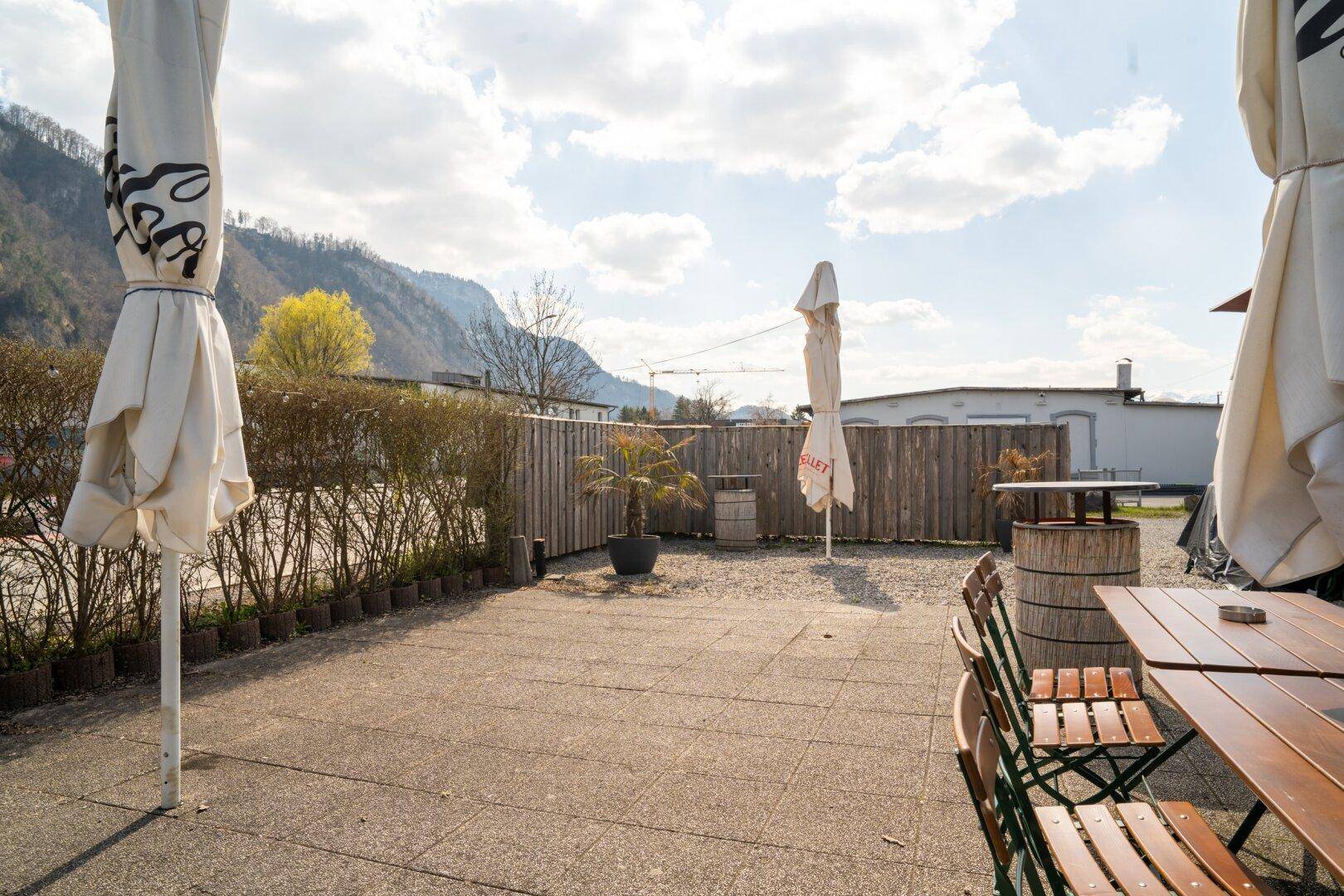 Geräumige Außenterrasse mit Tischen, Sonnenschirmen und Blick auf die umliegende Landschaft.