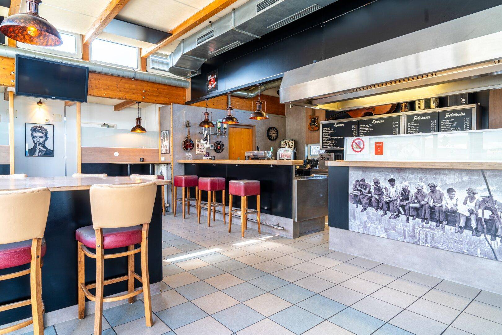 Blick auf die Bar und den Thekenbereich eines Restaurants mit Hockern und Speisekarten.