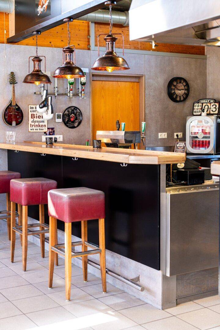 Detailansicht der Bar mit Zapfanlage, Hockern und rustikalen Hängelampen.