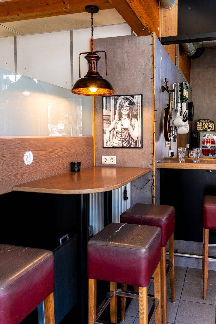 Kleiner Bartisch mit Hockern und Wanddekoration in einem Restaurant.