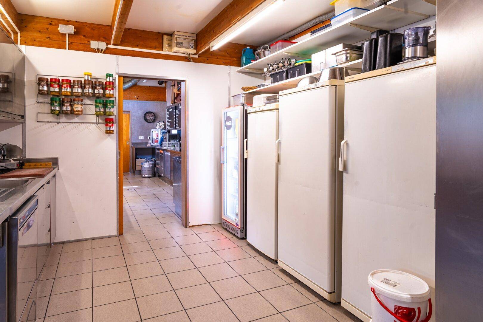 Lagerbereich einer Gewerbeküche mit mehreren Kühlschränken und Regalen für Vorräte.