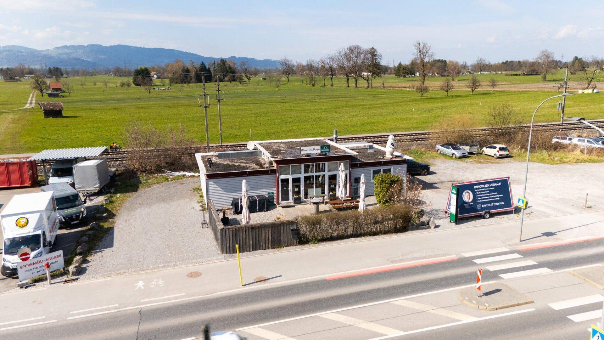 Luftaufnahme des Restaurants mit umliegenden Feldern, Parkplätzen und einer Straße.