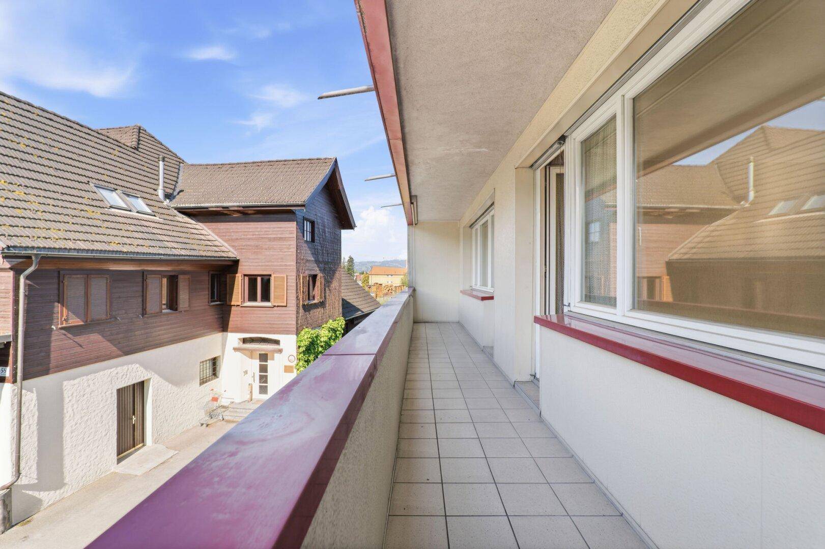 Langer Balkon mit Fliesenboden und Blick auf die umliegenden Gebäude.