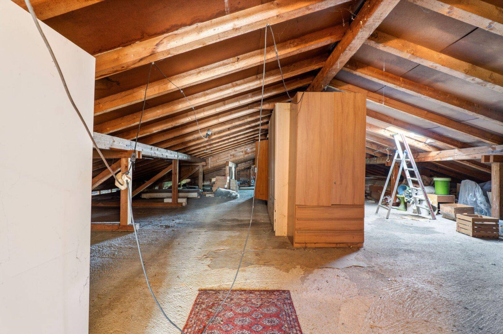 Unausgebauter Dachboden mit sichtbaren Holzbalken und viel Stauraum, ideal für zukünftige Nutzung.