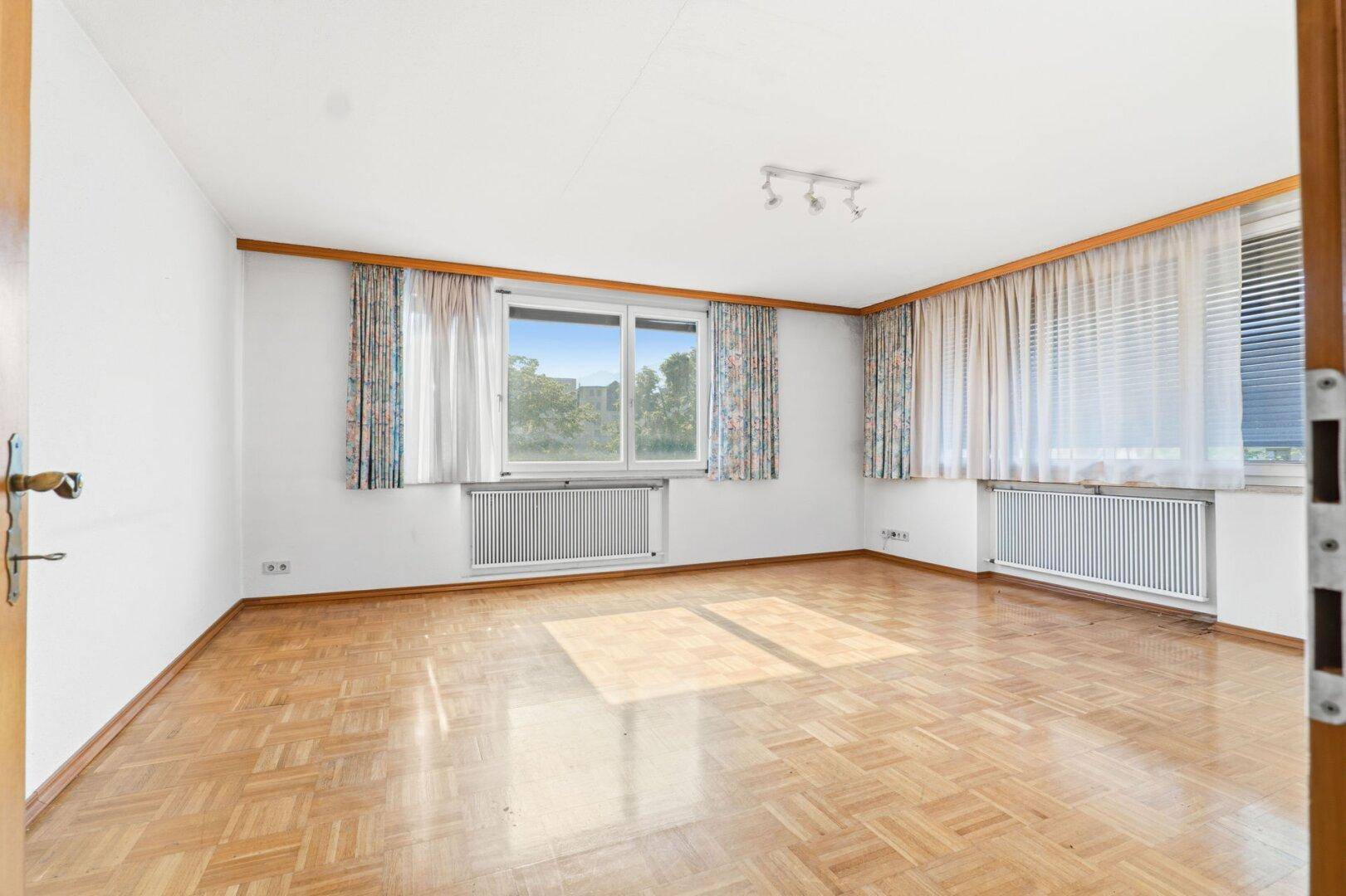 Geräumiges Zimmer mit Parkettboden, mehreren Fenstern und guter Belichtung, ideal für Wohnzwecke.