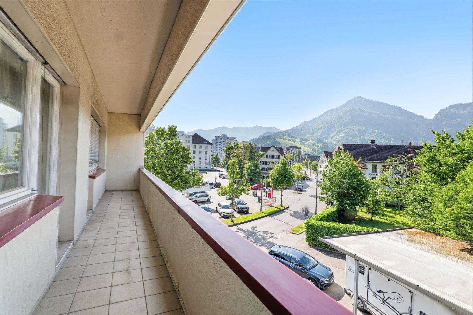 Geräumiger Balkon mit Fliesenboden und weitem Blick auf die Berge und die Stadt.