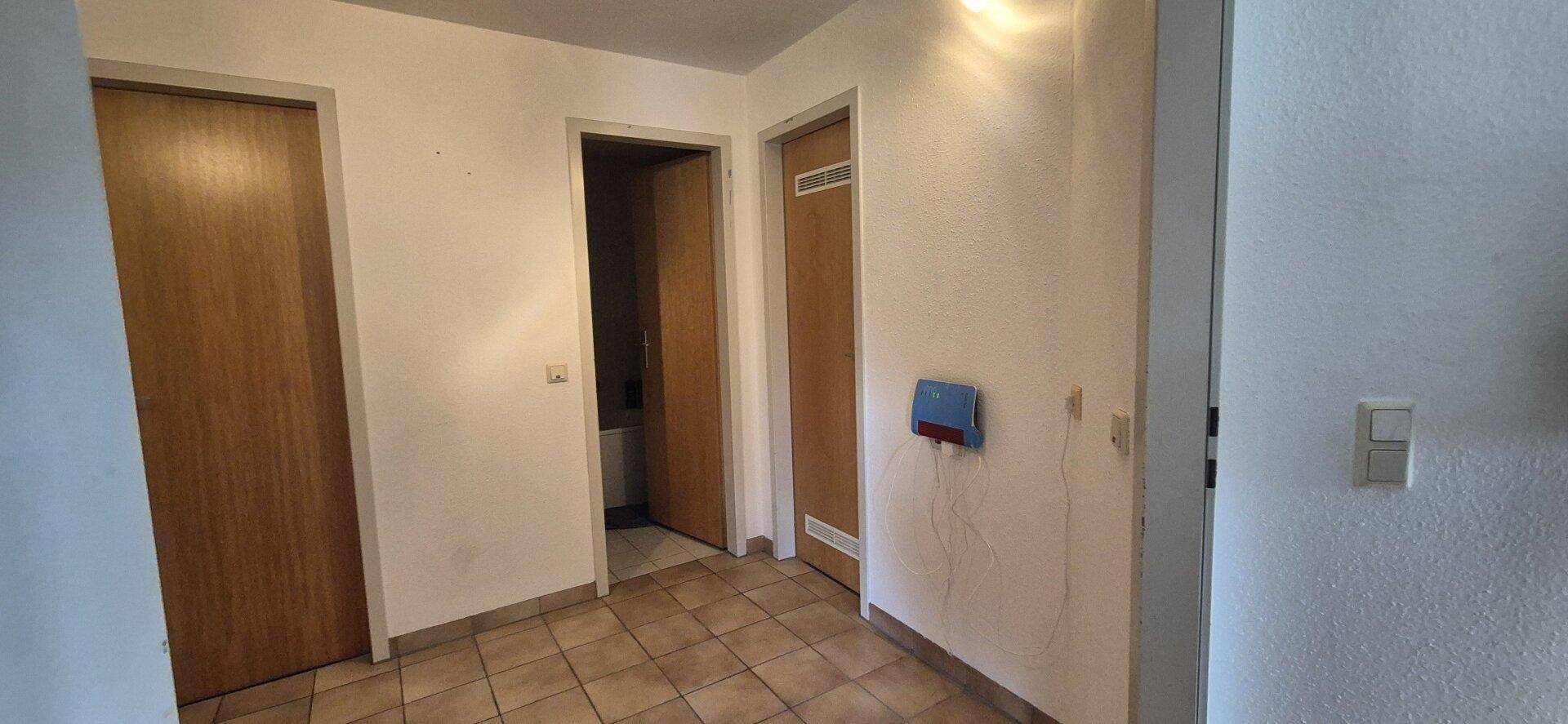 Flur mit Fliesenboden und mehreren Holztüren zu den Zimmern.