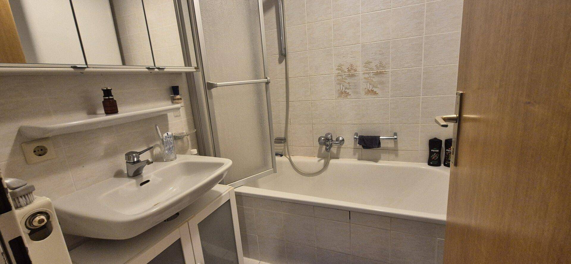 Badezimmer mit Badewanne, Waschbecken und Spiegelschrank.