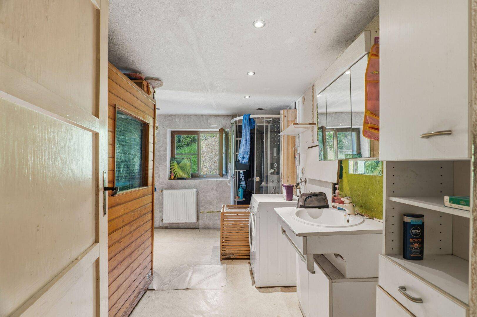 Geräumiges Badezimmer mit Dusche, Waschbecken, Waschmaschine und einem Fenster für Tageslicht.