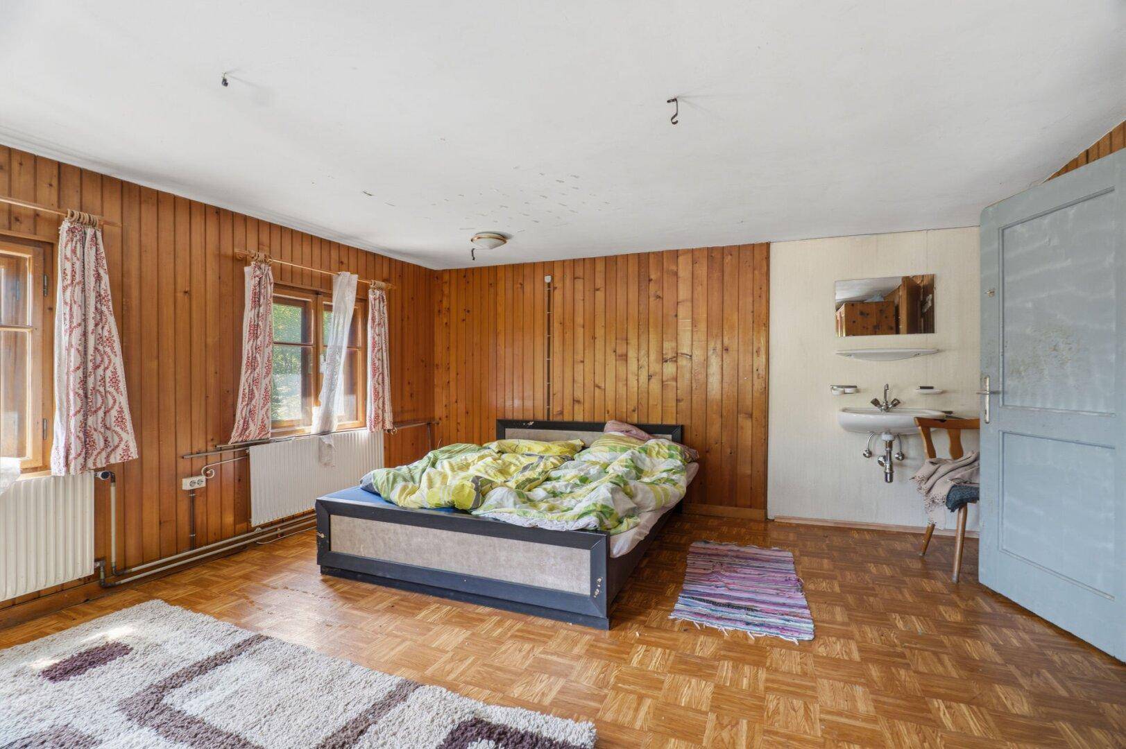 Helles Schlafzimmer mit Holzwänden, einem Bett und einem Fenster, bietet viel Gestaltungspotenzial.