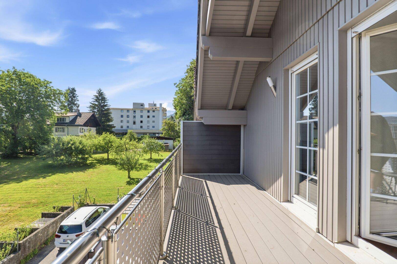 Balkon mit Metallgeländer und weitem Blick auf die grüne Umgebung.
