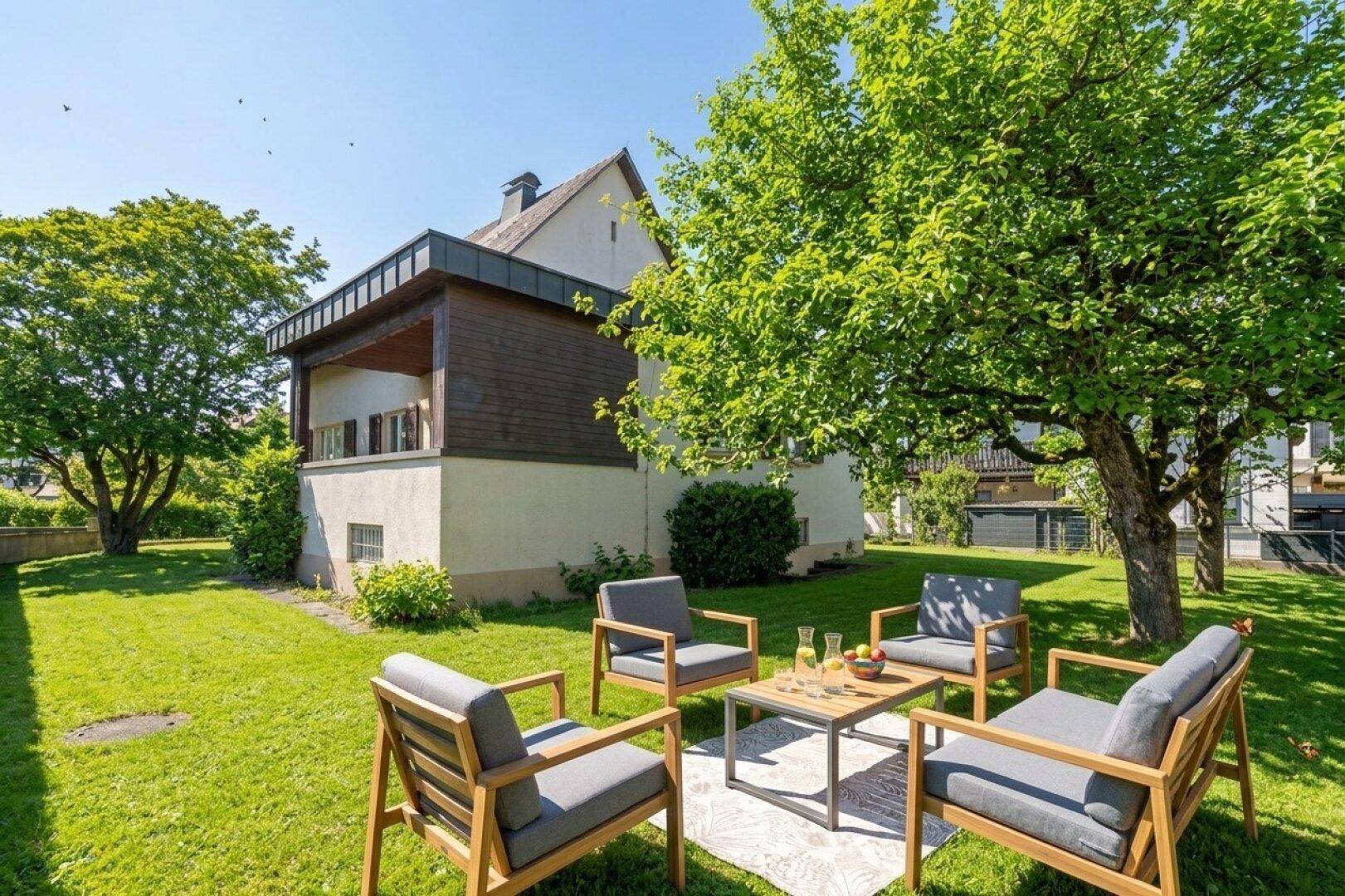 Gepflegter Garten mit modernen Gartenmöbeln und einem großen Baum, ideal zum Entspannen.