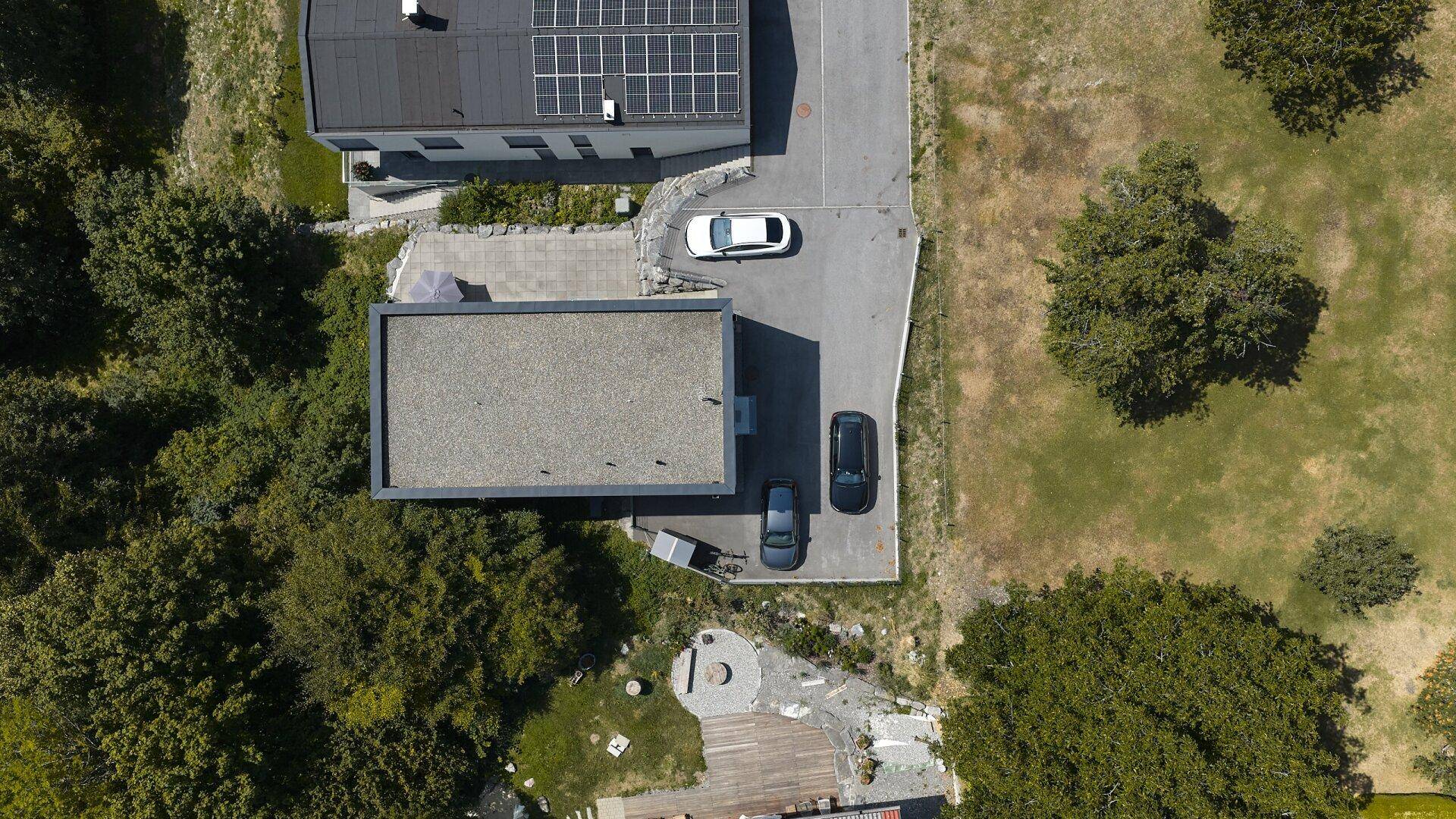 Senkrechte Luftaufnahme von modernen Gebäuden mit Flachdächern und Parkplätzen in grüner Umgebung.