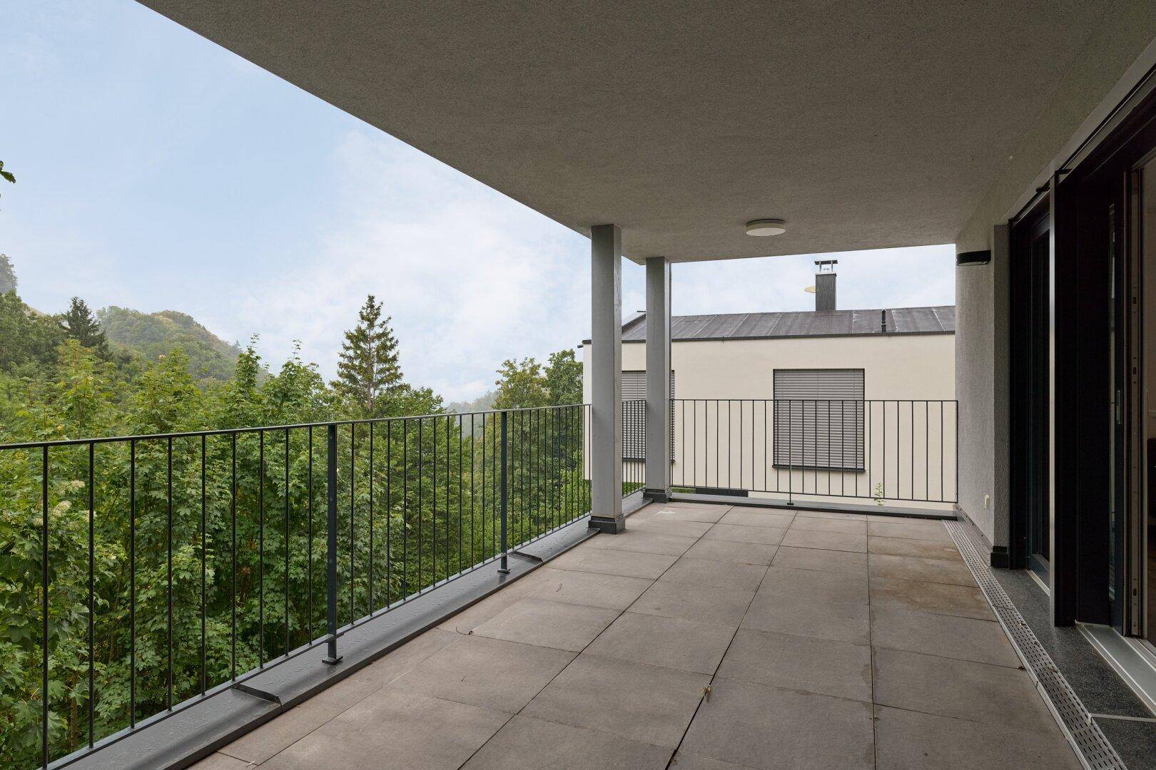 Geräumiger Balkon mit Fliesenboden und Blick ins Grüne, ideal für entspannte Stunden im Freien.